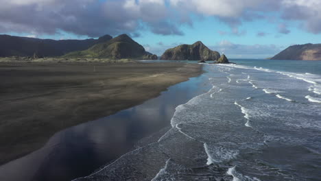 Flying-above-black-sandy-Whatipu-beach-towards-Huia-Reserve,-New-Zealand