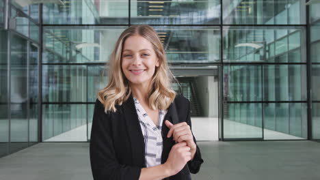 Portrait-Of-Businesswoman-Standing-In-Lobby-Of-Busy-Modern-Office