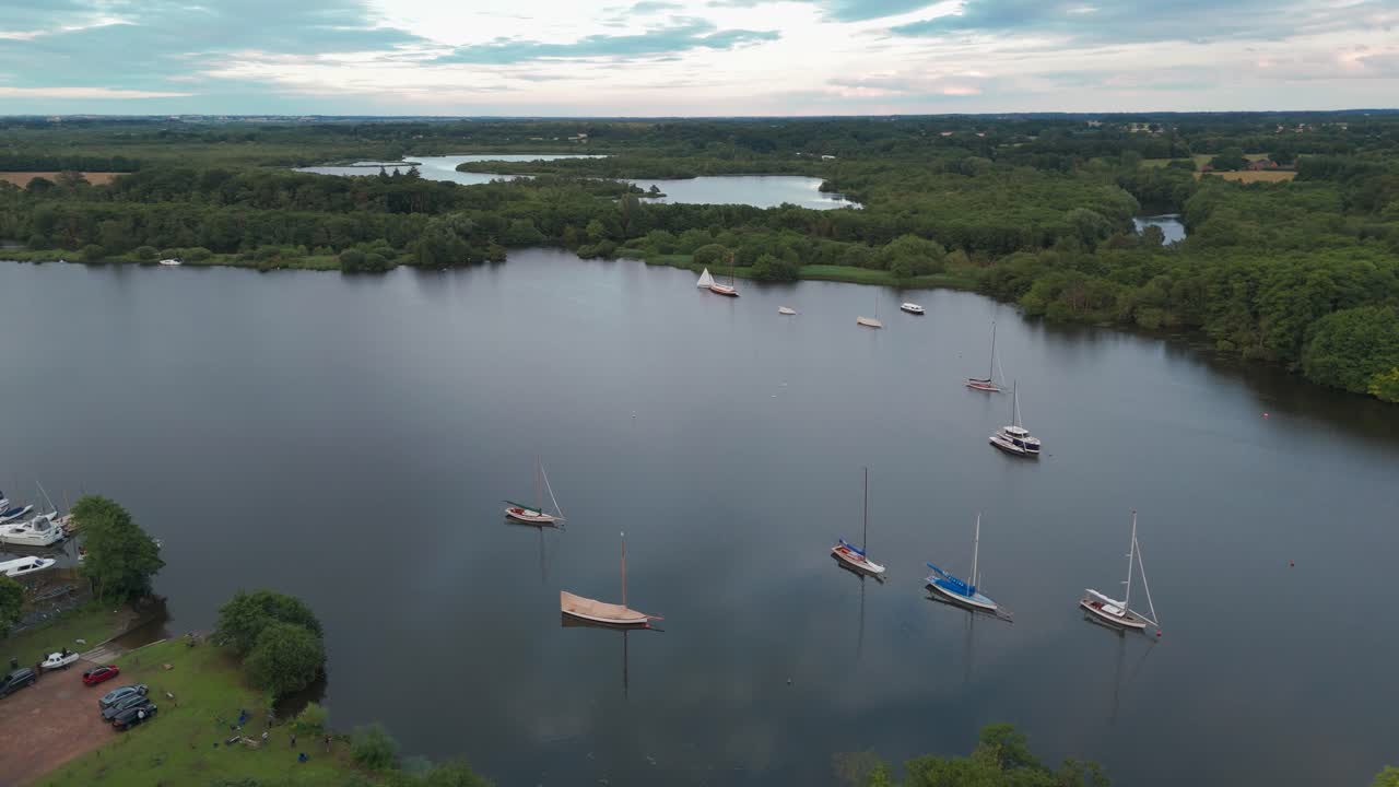 una vista aérea de un lago con varios barcos navegando en él, rodeado de árboles y un bosque
