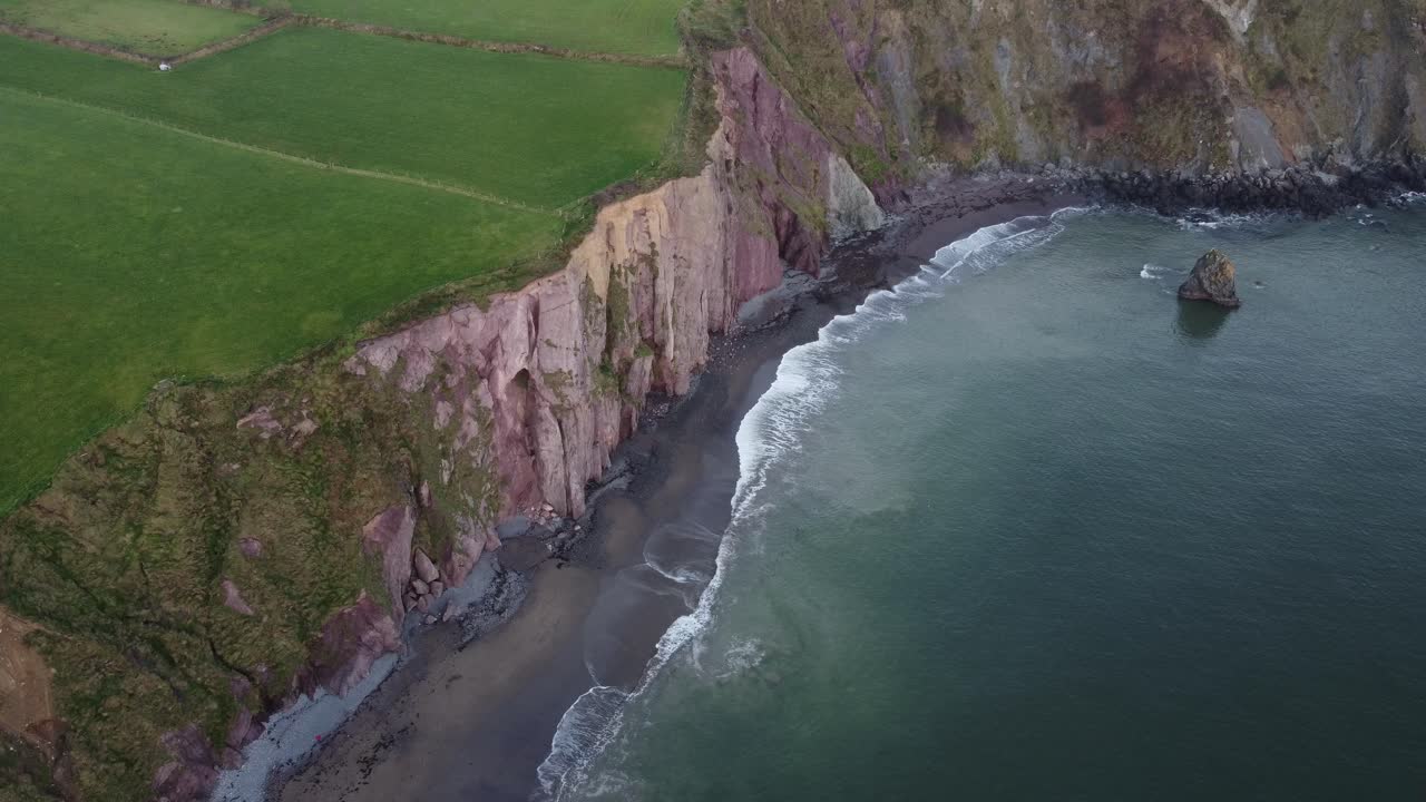 toma aérea cinematográfica de la playa y los acantilados en una tarde de invierno en la costa de cobre waterford irlanda