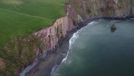 toma aérea cinematográfica de la playa y los acantilados en una tarde de invierno en la costa de cobre waterford irlanda