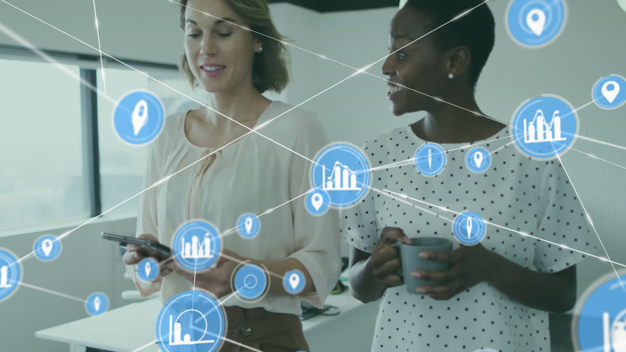 Animation of connected icons over diverse female coworkers walking and sharing ideas in office