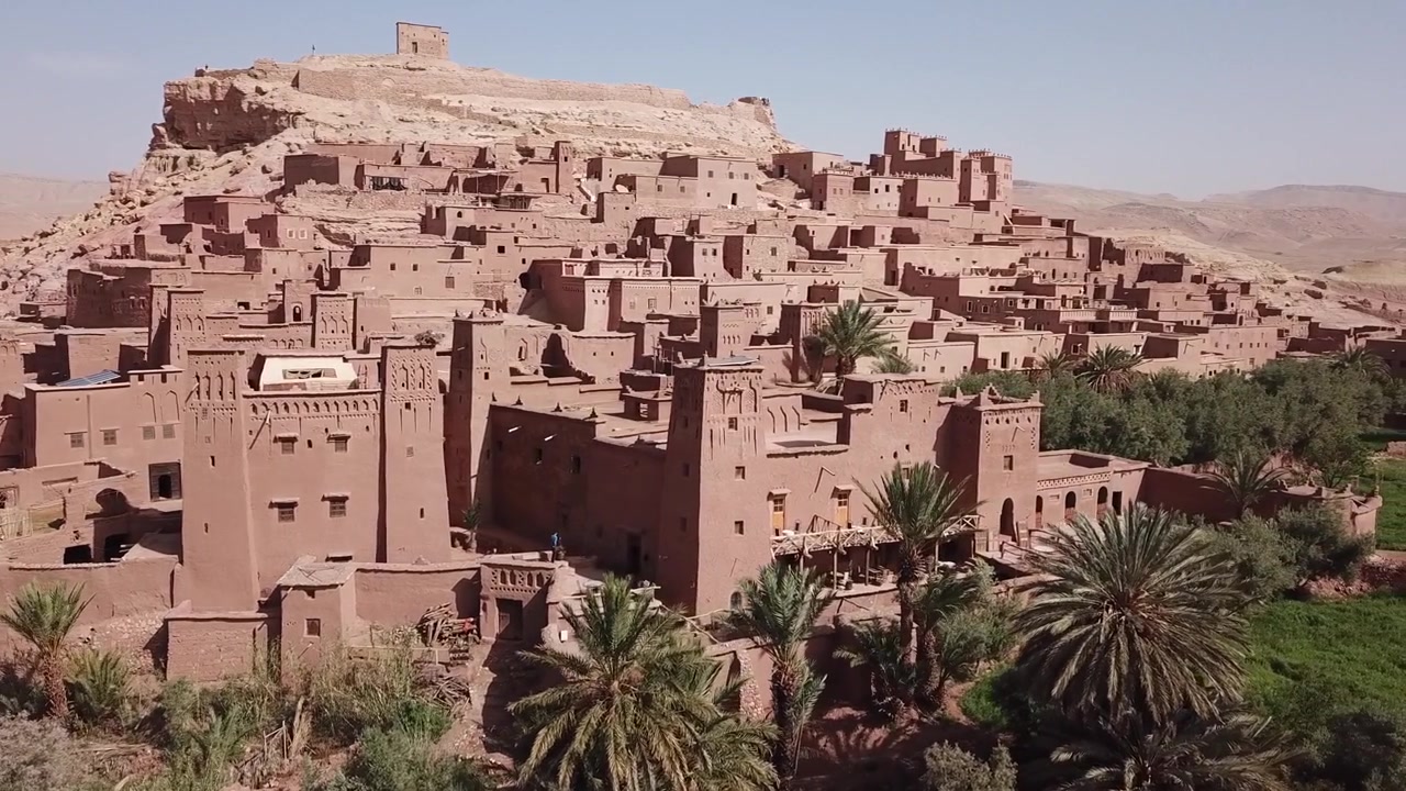 La kasbah di Ait Benhaddou si erge sopra una fitta oasi di palme a Ouarzazate. Iconico sito Patrimonio dell'Umanità UNESCO con edifici in adobe a strati e un forte contrasto desertico, ideale per viaggi e immagini cinematografiche