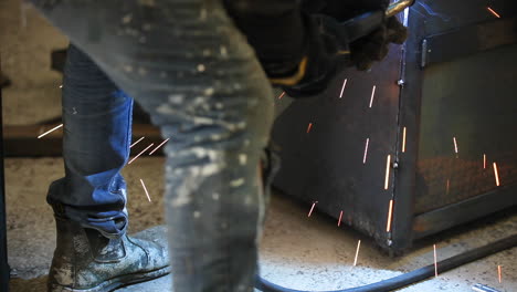 welder crouching beside project, moving tool down slowly to ensure the sheet is secure