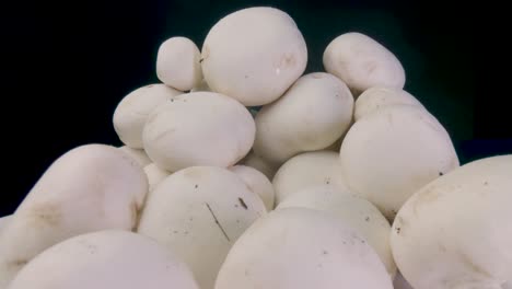 macro slide champignon mushrooms on a black background. probe lens dolly shot. organic food concept. the camera moving through a pile of mushrooms. close-up. type c.