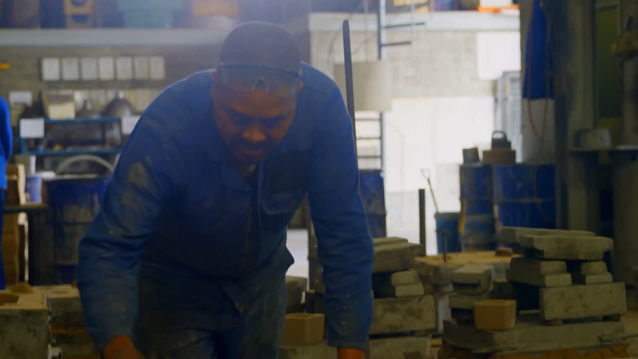 Trabalhador organizando molde de metal em oficina de fundição 4k