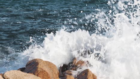 slow motion of awesome power of waves splashing over rocks on a sunny day