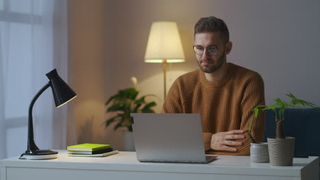 Retrato-De-Un-Participante-Masculino-De-Un-Video-Chat-De-Trabajo,-Un-Hombre-Asiente-Con-La-Cabeza-Viendo-La-Pantalla-De-Una-Computadora-Portátil-Sentada-En-Casa-Durante-La-Comunicación-Remota-Por-La-Noche