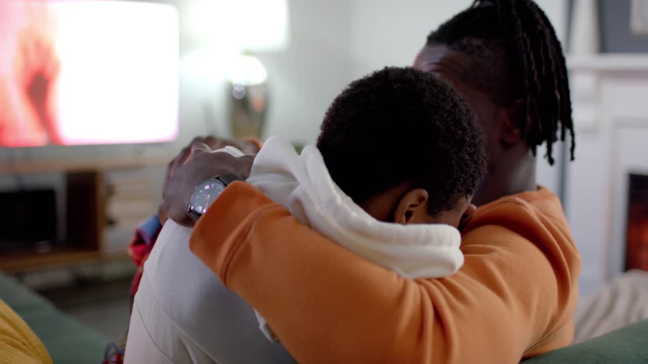 una pareja afroamericana relajándose viendo televisión en casa, en cámara lenta
