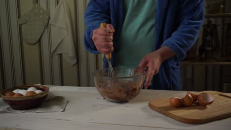 hombre batiendo ingredientes para hornear en un tazón de vidrio en la cocina. pastel casero
