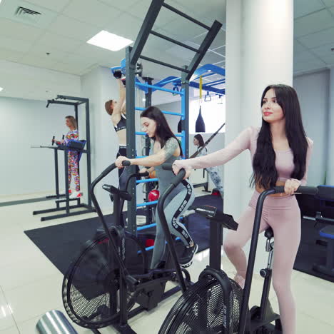 atractive young girls in sportswear are training hard in the sport club. active women doing workouts on modern simulators indoors on the light gym background. camera moves round.