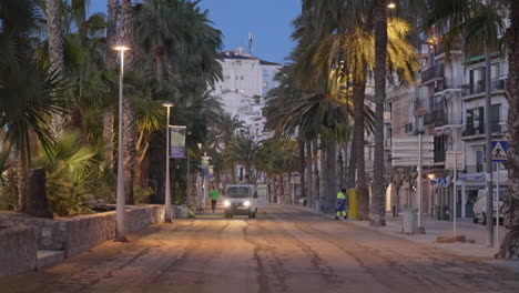 Paseo-Marítimo-De-La-Ciudad-Europea-Con-Palmeras-Y-Edificios,-Hombre-Corriendo-Al-Anochecer