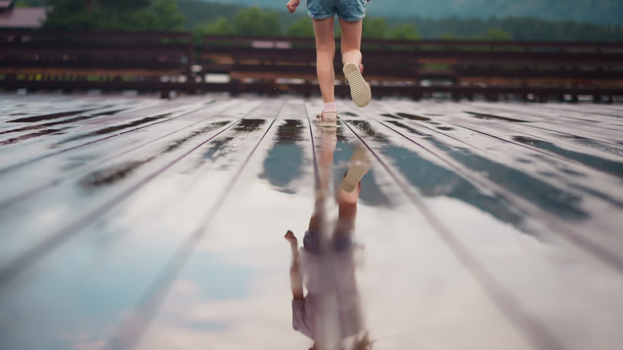 작은 소녀 가  ⁇ 은 표면 에 반영 된 땅 을 따라 달리고 있다