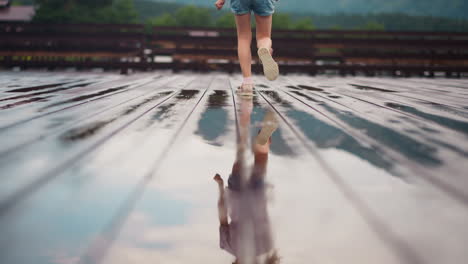 una niña pequeña corre por el suelo reflejándose en la superficie húmeda