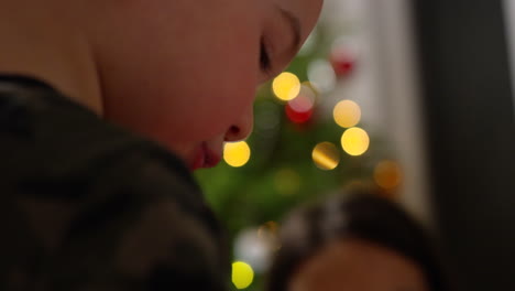 Toddler-boy-and-mother-decorate-gingerbread-house-for-christmas---close-up-on-toddlers-face