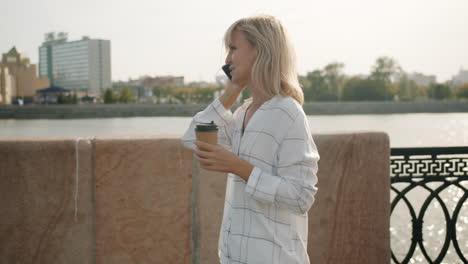 woman walking and talking on phone, enjoying coffee outdoors