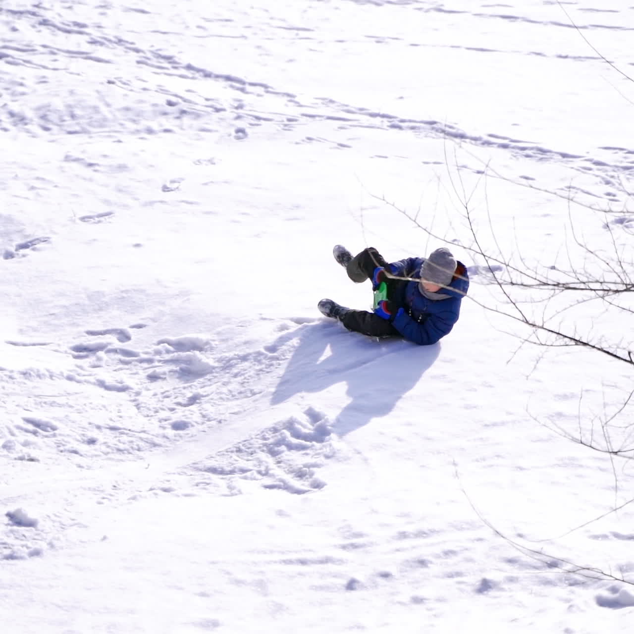 Winter sledding from snowy slides. Boy on a plastic sled riding downhill. Winter holidays. Slow motion.