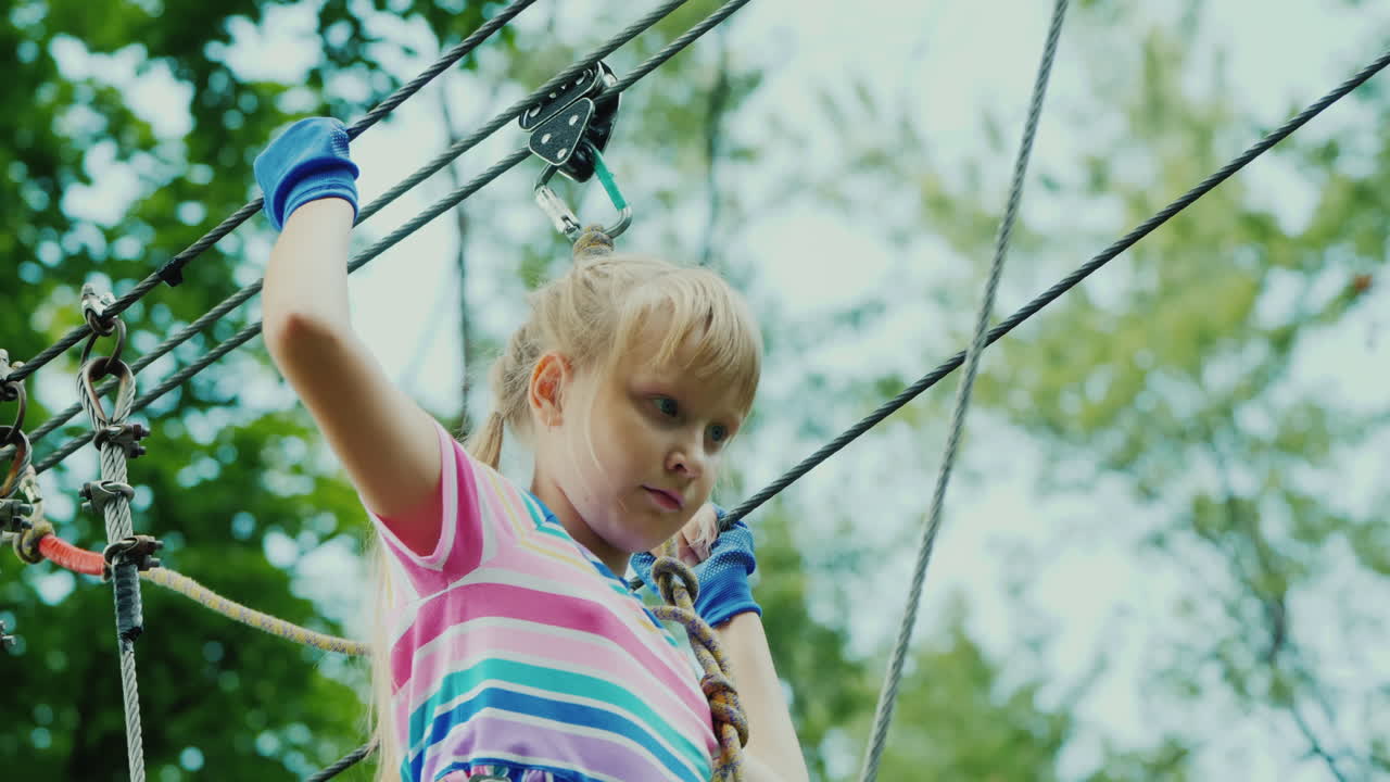 entretenimiento en el campamento de verano - un niño aprende a usar cables de seguros trepa alto en las ramas de