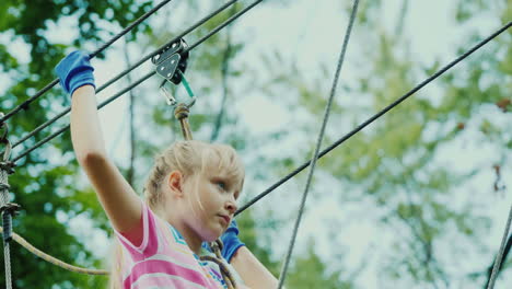 entretenimiento en el campamento de verano - un niño aprende a usar cables de seguros trepa alto en las ramas de