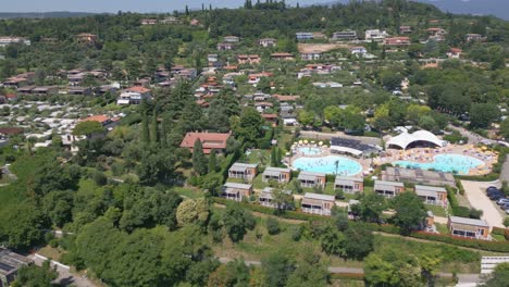 Toma-Aérea-De-La-Piscina-Del-Camping-Europa-Silvella-Y-La-Naturaleza-En-El-Lago-De-Garda,-Italia