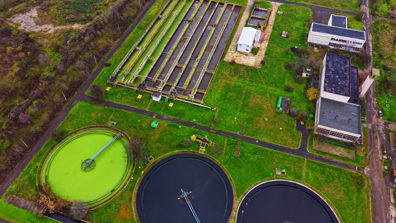 Water treatment facility with circular tanks and green areas seen from above during daylight hours