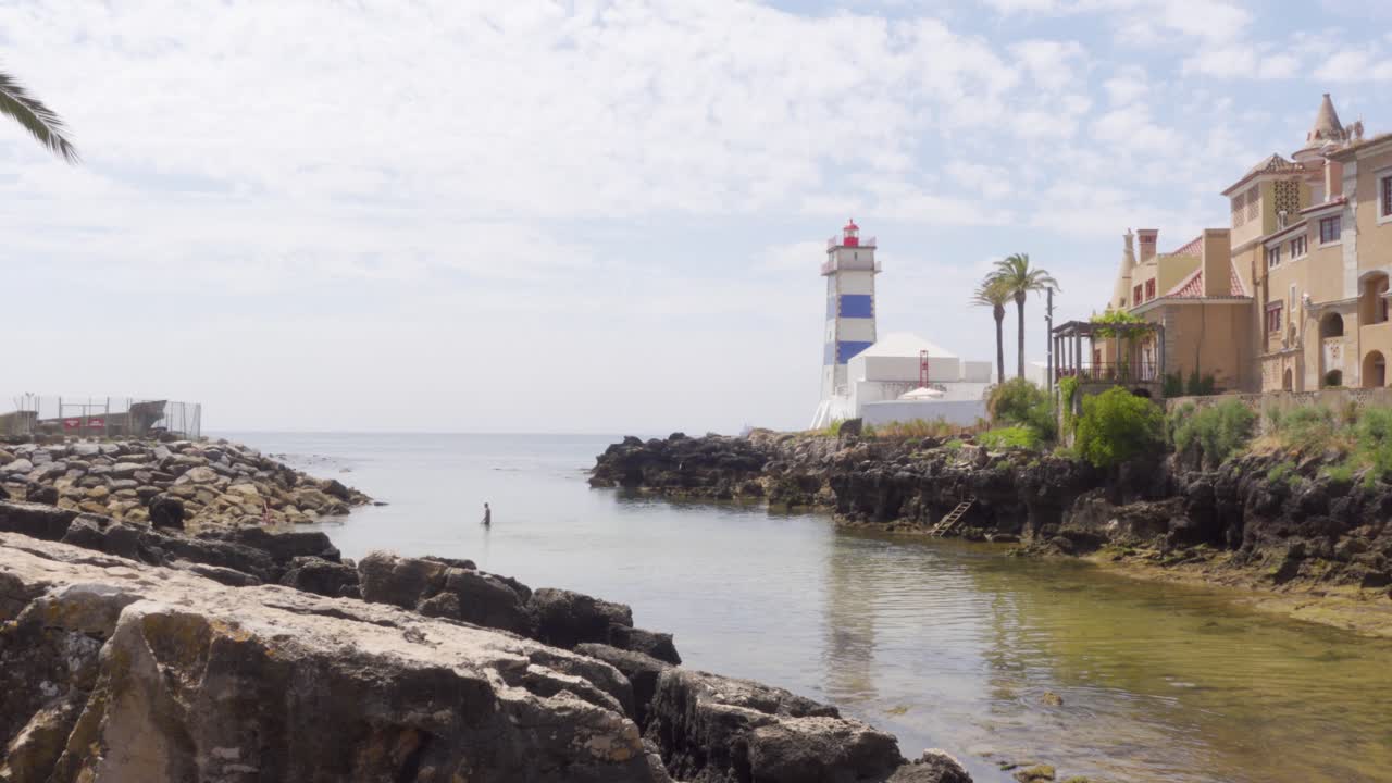 una persona en el agua junto al faro de santa marta en cascais, portugal