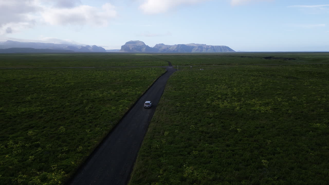 Car on remote Iceland road, vast fields, adventure, serenity