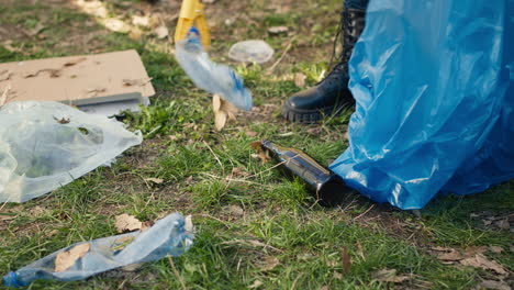 volunteer using tongs tool to collect trash and plastic waste from the woods