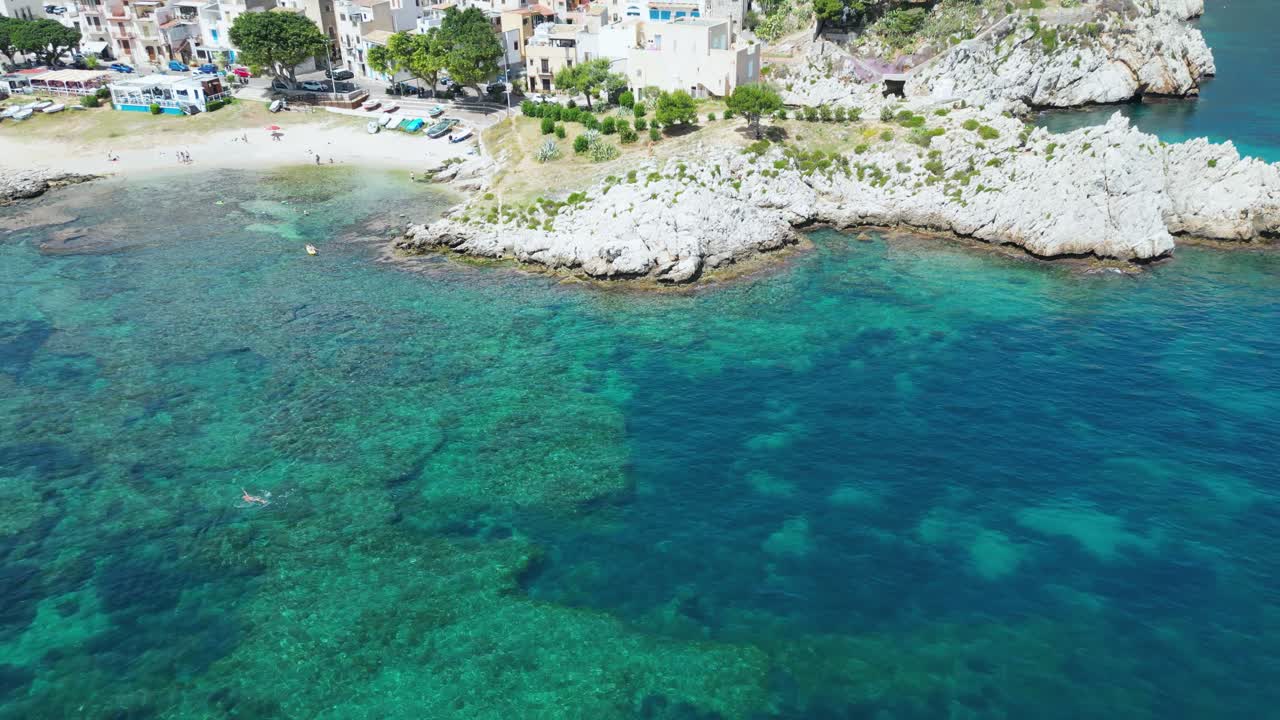 Aerial drone footage of Sant’Elia cove in Sicily: turquoise sea, rocky coastline, hidden beach, and Mediterranean charm. Perfect for travel, nature, and summer holiday projects