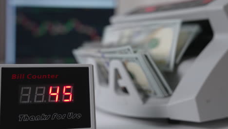 bill counter showing quickly changing numbers of money counted. dollars being counted in the equipment at backdrop in blur.