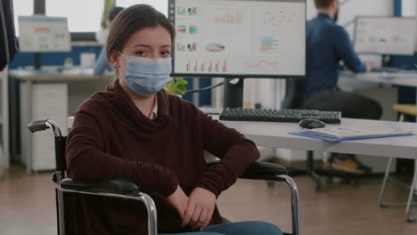 woman employee with disabilities with protection mask looking at camera