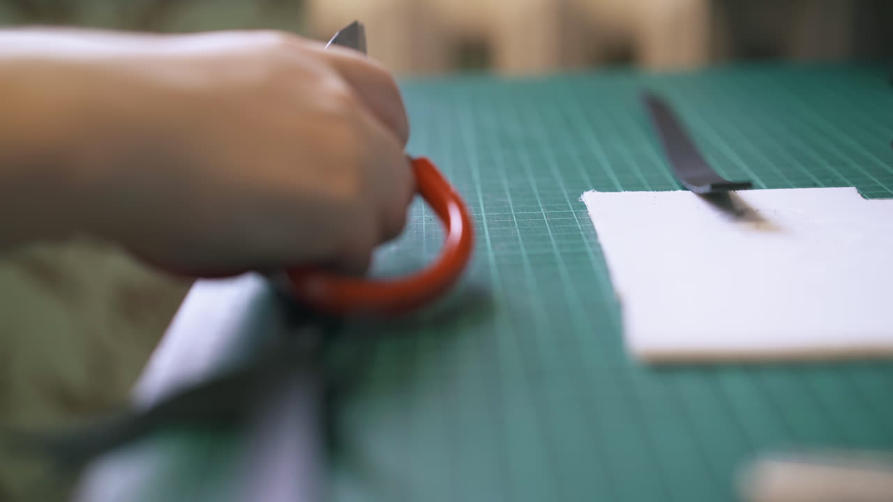 una niña experta en diseño mide y corta tiras de cuero negro