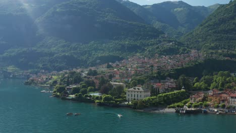 lush greenery surrounds lake como in ossuccio, italy, boats gently drift, mountain backdrop