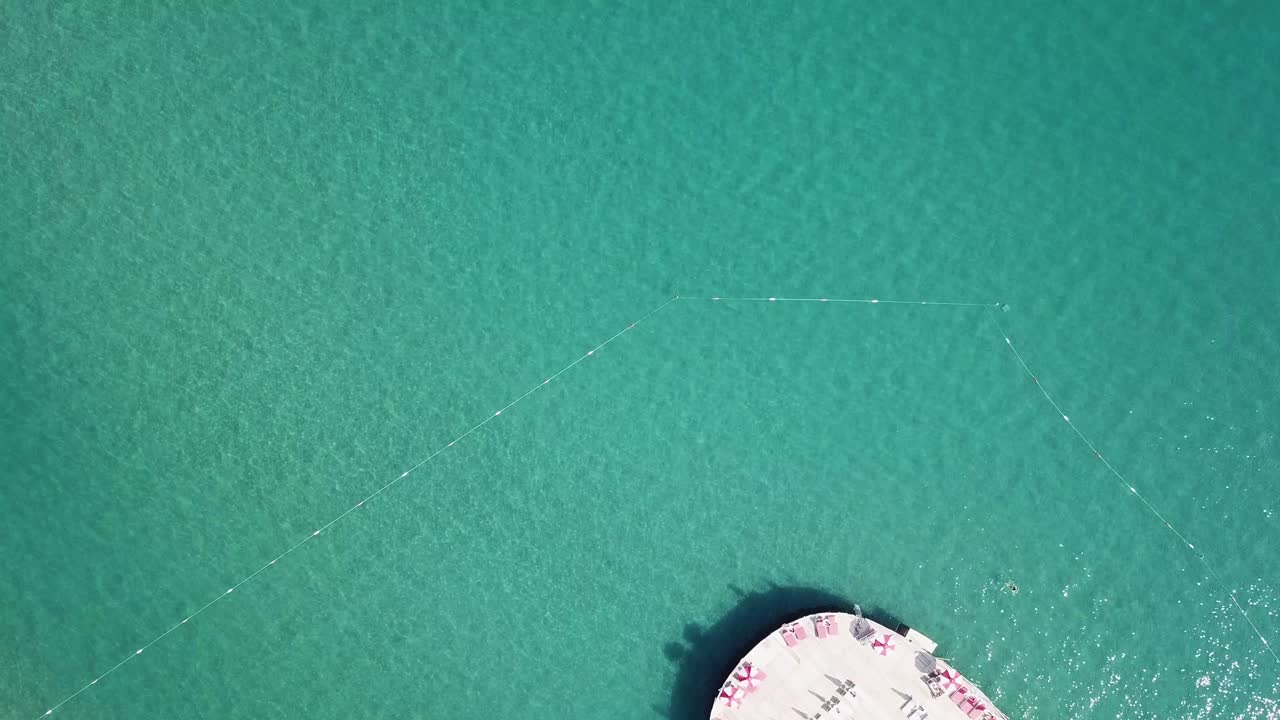 Vista aerea di una spiaggia turchese con boe galleggianti e beach club