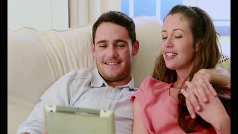 pareja linda usando una tableta en el sofá
