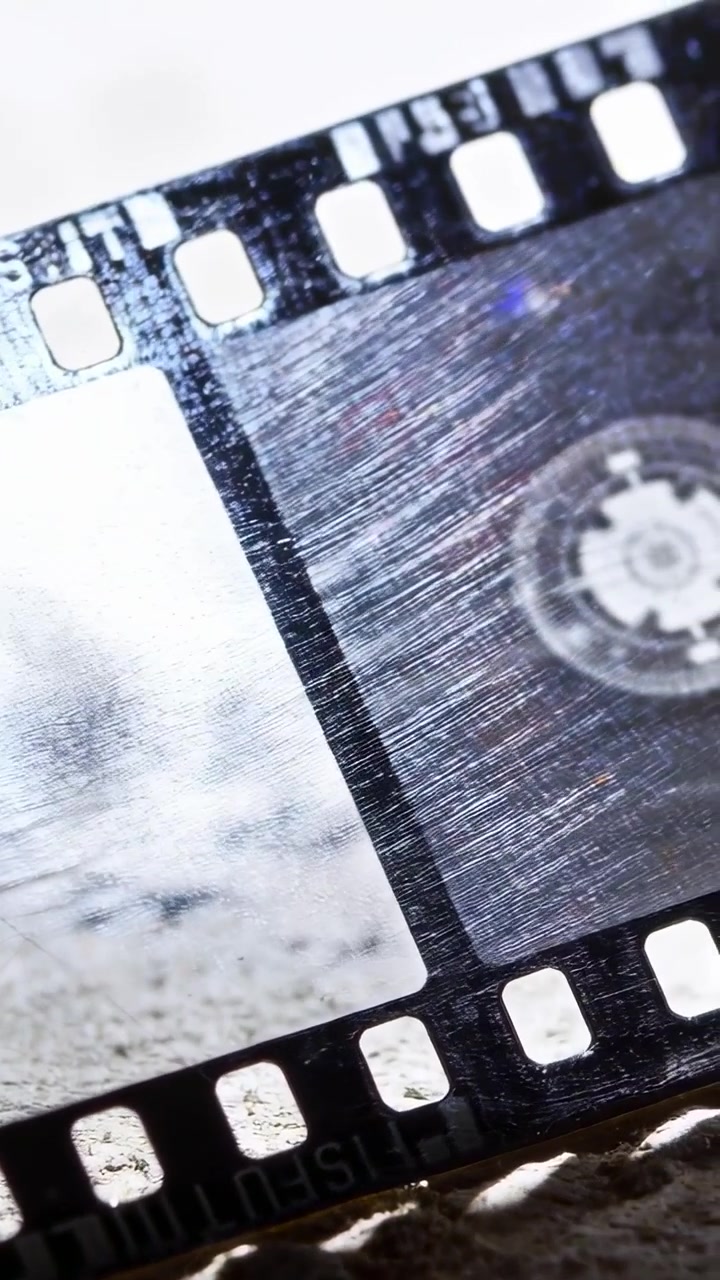 Video verticale: Telecamera che si sposta rivelando una striscia di pellicola da 35mm su un tavolo per l'ispezione della texture.
