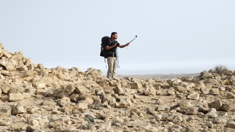 A-man-standing-on-the-edge-of-the-crater-surrounded-by-boulders-takes-a-selfie