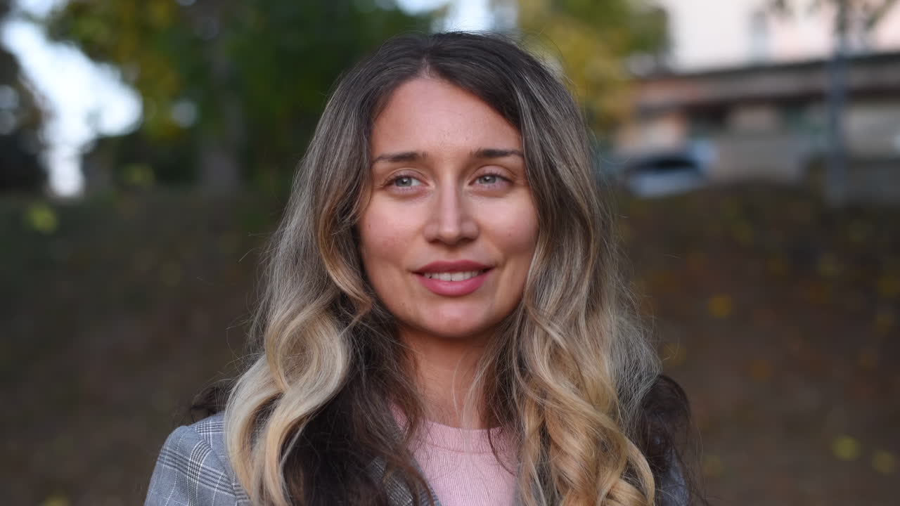 Close up of a blonde woman smiling at the camera in the park