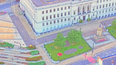 drone view of barnsley war memorial in front of the neoclassical town hall, with red poppy wreaths, symmetrical formal garden layout, stepped plaza, and clean civic architecture at sunset