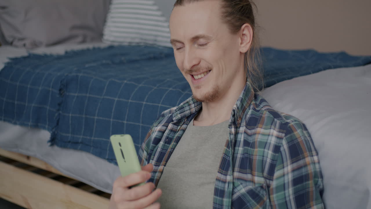 Man using mobile phone and credit card for online payment and dancing to music in bedroom