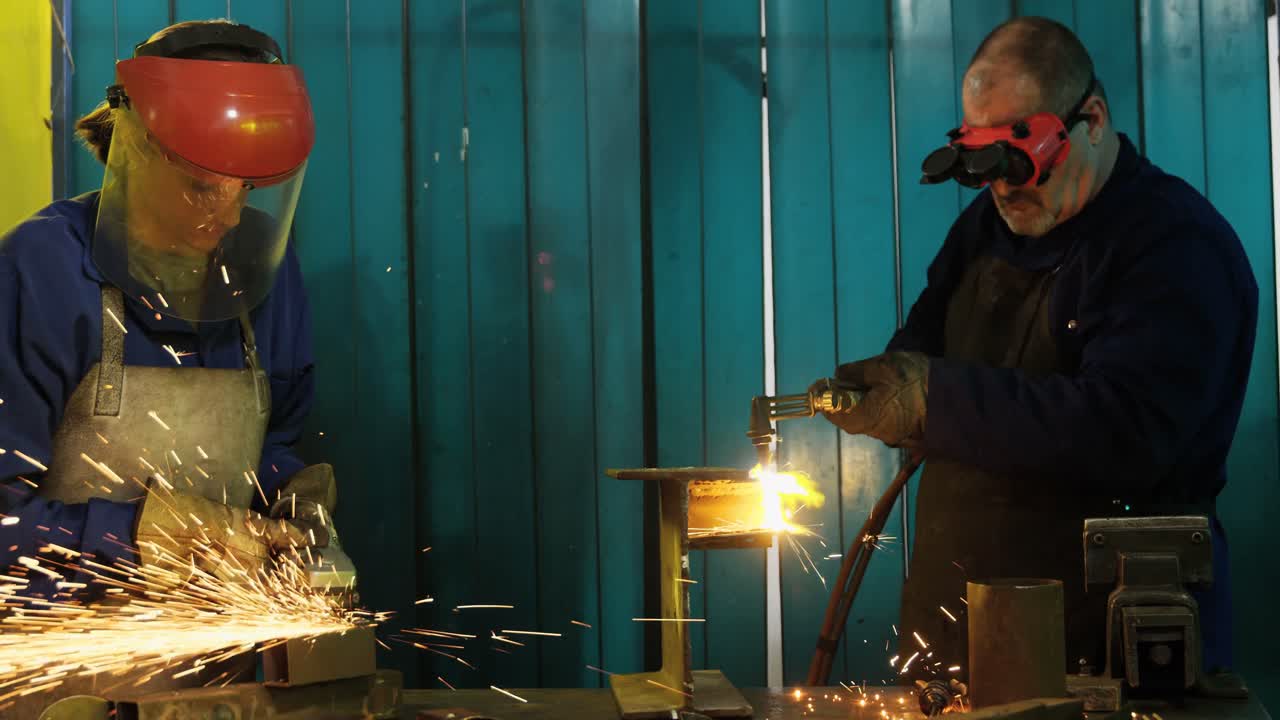 Male and female welders working in workshop
