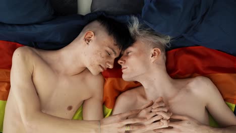 Two-gay-men-lovers-lying-side-by-side-on-flag,-LGBT-concept,-slow-motion