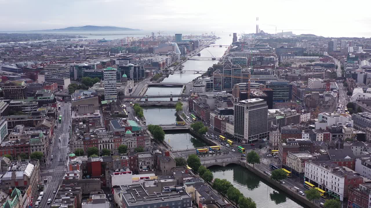Daytime in the middle of Dublin’s busy city centre. Overlooking the river Liffey as it meets the sea. The flyover shows a dull sky with clouds covering most of it.