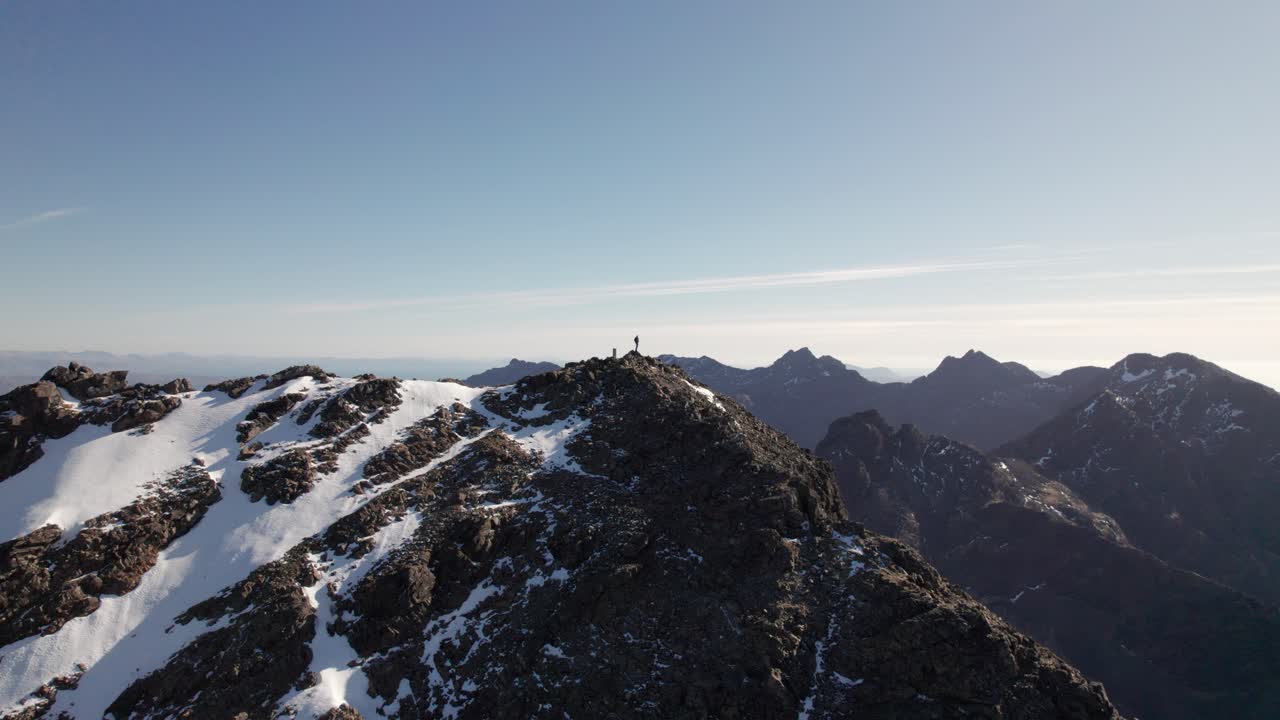 hombre de pie en la cima de las montañas cuillin en escocia en un día soleado