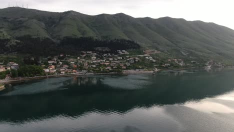 Drone-view-in-Albania-flying-over-Shkodër-lake-in-Pogradec-on-cloudy-day-with-green-mountains-on-the-back