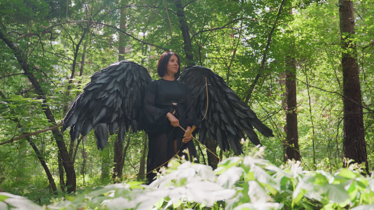 Forest warrior with bold look and massive black wings stands among flowers holding bow, sunlight illuminating her calm yet fierce presence, fantasy moment filled with elegance