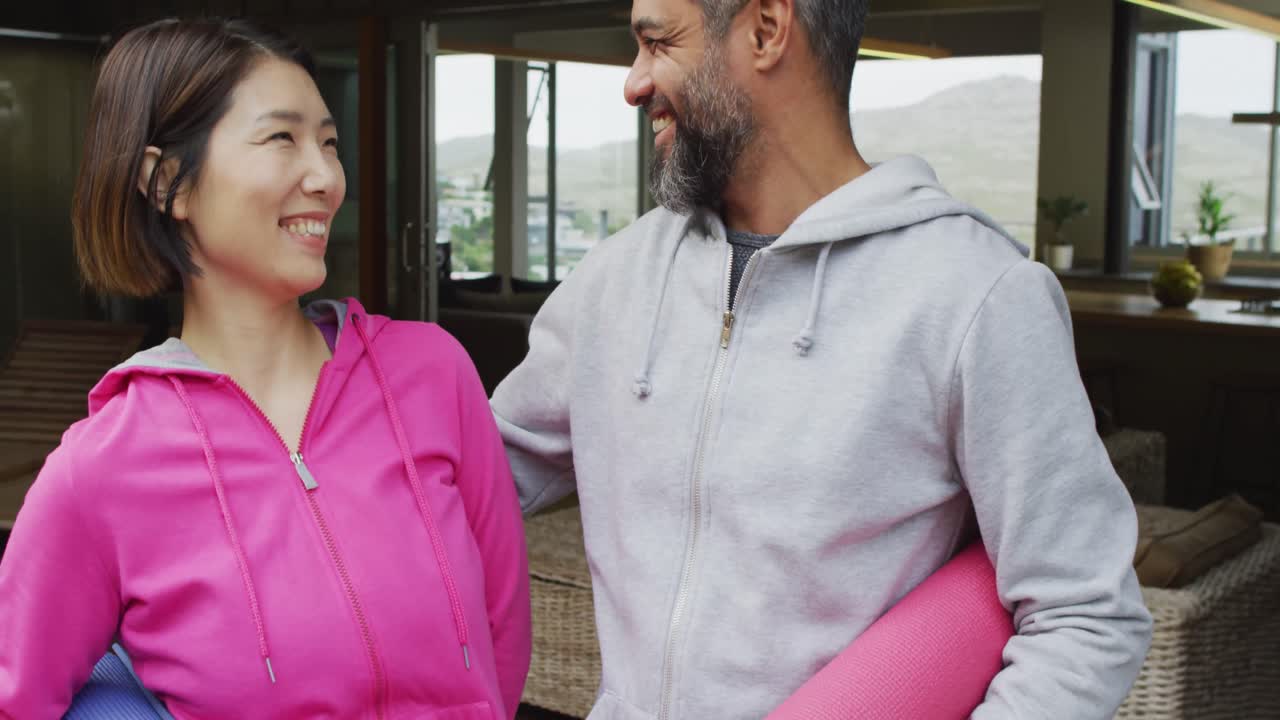 행복 한 다양한 커플 의 초상화 가 매트 를 들고 테라스 에서 미소 짓고 있다