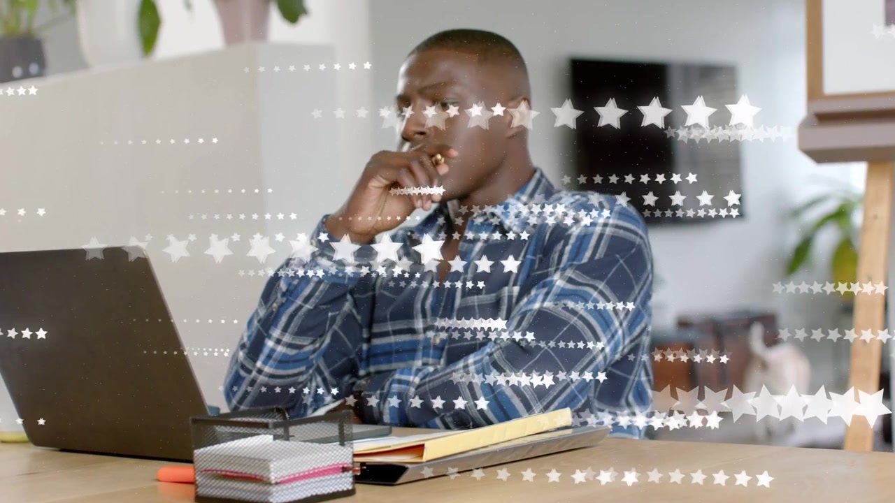 Hombre tecleando en un portátil sobre una mesa con un gráfico de estrella pasando, mientras sostiene gafas estudiando TI