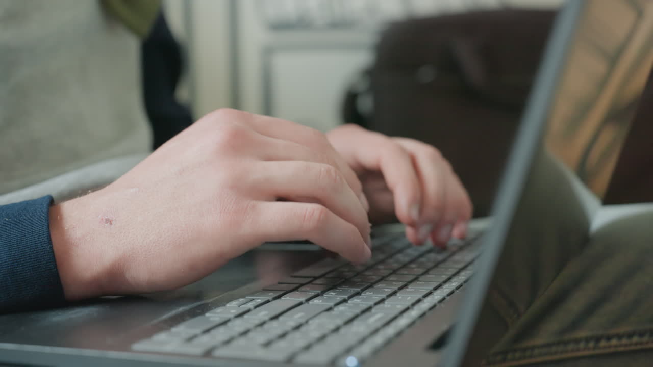 Mani in primo piano che digitano su un laptop, professionista che lavora durante il tragitto, borsa da lavoro sullo sfondo, tempi stretti, leggera sfocatura di movimento, luce fluorescente, battiture ritmiche, pressione della scadenza