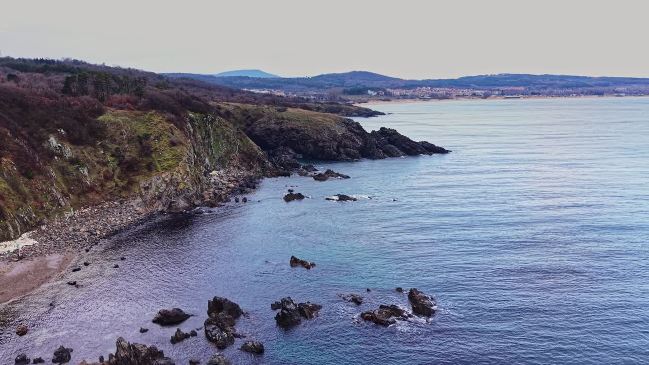 Kystlandskab med klippekyst og roligt vand ved solnedgang